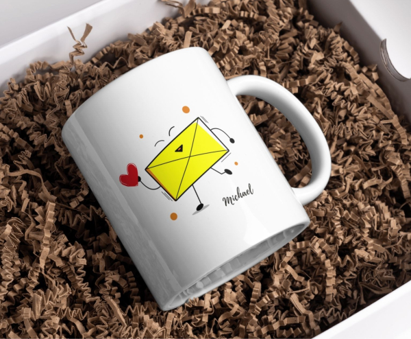 Keramiktasse mit gelbem Umschlag-Motiv, Herzsymbol und Name „Michael“, präsentiert in Geschenkbox mit braunem Füllmaterial.